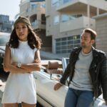 Man and Woman Standing Beside White Car Having A Discussion