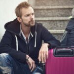 a man sitting next to a purple suitcase