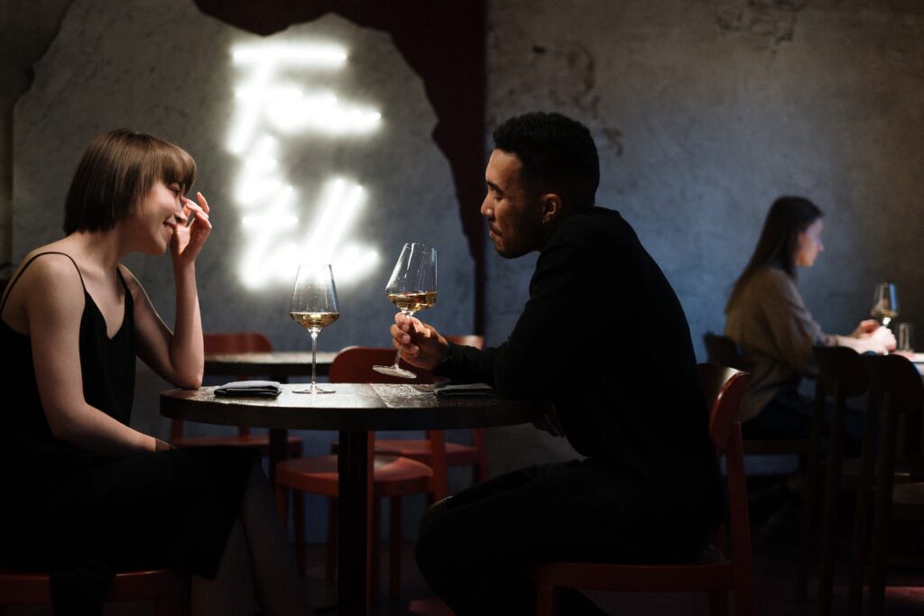 Man in Black Long Sleeve Shirt Sitting on Chair enjoying his first date with pretty lady